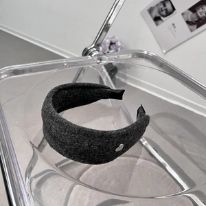 Détail du bandeau en tissu épais gris foncé avec un petit ornement en métal en forme de cœur