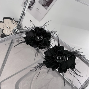 Detail von zwei schwarzen Blumen-Haarklammern mit Federn auf einem Display-Ständer