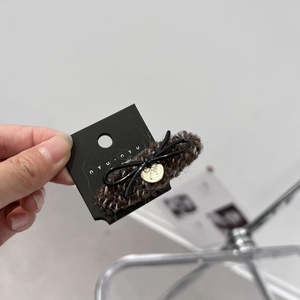 Close-up of brown knit hair claw with black bow and gold pendant detail
