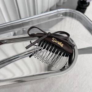 Détail d'un peigne à cheveux en cuir marron orné d'un emblème Smile doré élégant