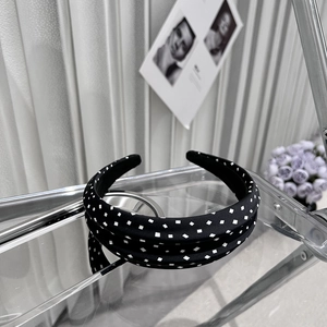 Detail of a wide black polka dot padded headband on a reflective stand with vintage vibe