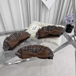 Detail view of retro plaid bow banana hair clips on a minimalist display stand