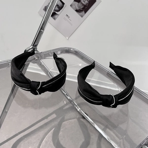 Detail eines schwarzen Satin-Haarreifs mit Knoten und elegantem Strassbesatz am Rand