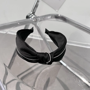 Detailaufnahme eines schwarzen Satin-Knoten-Haarreifs mit schimmernden silbernen Strasssteinen