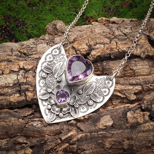 Detail showing vintage heart pendant with purple gems on rustic tree bark background