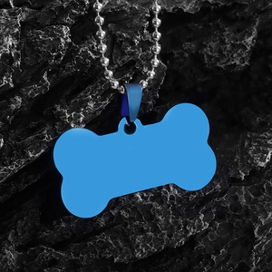 Detailed macro view of a blue bone-shaped pet ID tag with a silver ball chain on dark rock