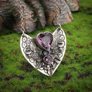Vintage silver alloy necklace featuring double purple heart stones on mossy background