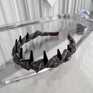 Close-up of brown plaid fabric headband with secure black teeth and butterfly button