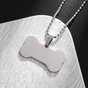 Close-up of polished stainless steel bone-shaped pendant with a matching bead chain