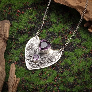 Bohemian silver necklace with twin heart purple gemstones on a forest moss background