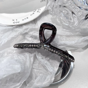 Detailed close-up of dark purple bow hair claw clip with grey rhinestones and pearls