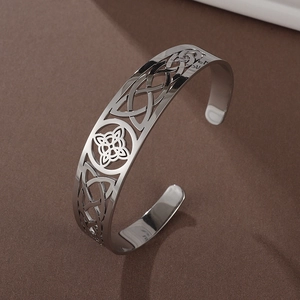 Macro detail of silver C-shaped open cuff bracelet featuring intricate Celtic knot hollow pattern