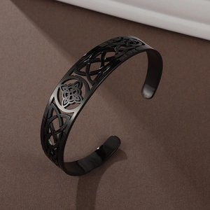 Macro detail of black stainless steel cuff with Celtic knot openwork and floral emblem