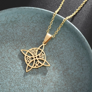 Detailed view of golden witch knot pendant necklace with mystical occult symbols on ceramic