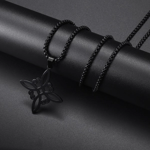 Detalle macro de un colgante de nudo de bruja negro mate con cadena cuadrada en soporte