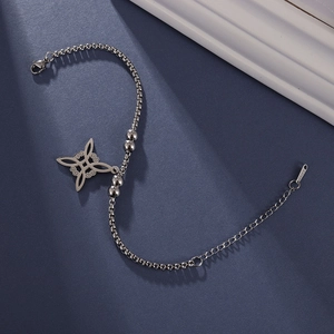 Detail eines silbernen Hexenknoten-Armbands aus Edelstahl mit Perlen auf blauem Grund