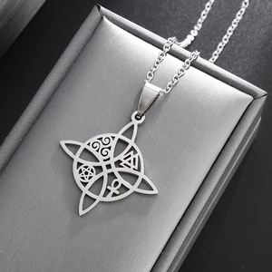 Macro shot of silver stainless steel witch's knot pendant with mystic symbols on grey texture