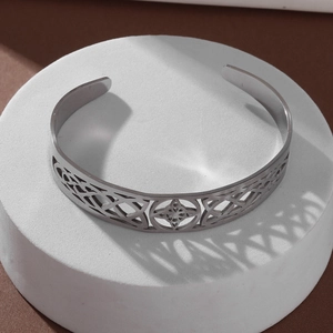 Macro detail of silver stainless steel witch knot bangle showing intricate celtic patterns