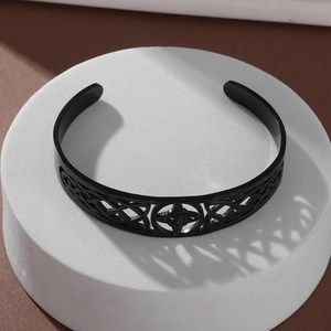 Close-up of black stainless steel open cuff bracelet with intricate Celtic knot patterns