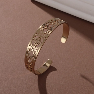 Macro shot of gold stainless steel open bangle featuring vintage Celtic knot hollow patterns