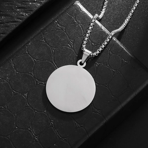 Close-up of a round stainless steel pendant with a brushed finish on a box chain