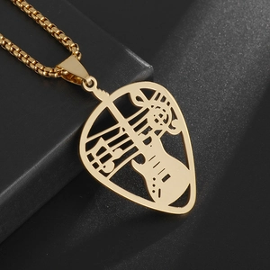 Macro shot of gold guitar pick pendant with hollowed music notes on black gift box