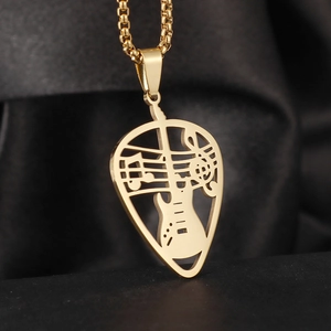 Macro shot of gold guitar pick heart pendant with musical notes on black silk