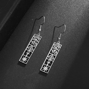 Detailed close-up of Eye of Horus hollowed stainless steel earrings on a black background