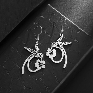 Macro detail of silver stainless steel hummingbird and flower earring with hollow tribal texture