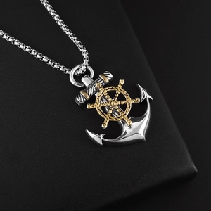 Macro detail of nautical anchor and helm pendant with silver and gold two-tone metallic finish