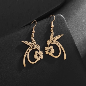 Macro detail of golden hummingbird and flower earrings with delicate hollow-out craft