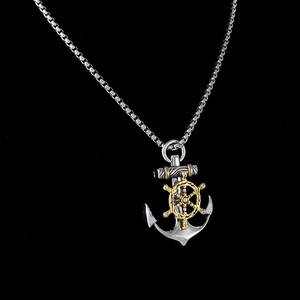 Close-up of silver anchor and golden helm pendant with a square box chain necklace