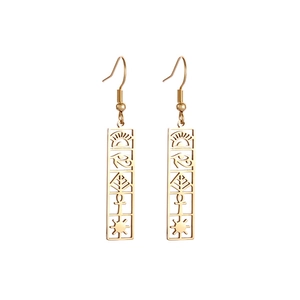Detailed view of golden Eye of Horus rectangular earrings with Egyptian symbols