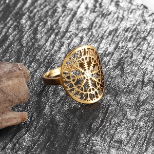 Macro detail of golden Viking ring with compass pattern on a dark stone background