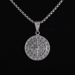 Macro detail of silver stainless steel compass pendant with engraved N E S W direction markers