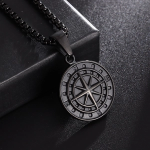 Macro detail of men's vintage stainless steel compass pendant with N E S W engraving
