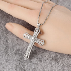 Close-up of silver cross pendant with double-layer hollow frame and pave-set zircons