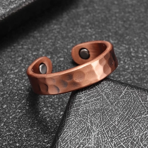 Macro detail of men's copper magnetic therapy ring with hammered texture and magnets