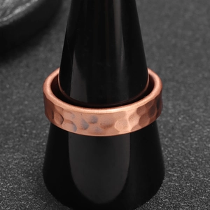 Textured copper ring with hammered surface finish on a professional jewelry display stand
