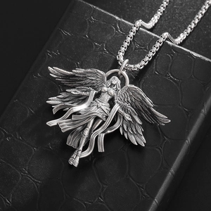 Macro shot of silver seraphim angel pendant showing detailed wings on black leather box
