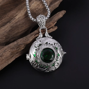 Macro side view of vintage silver locket pendant with carved patterns and green gemstone