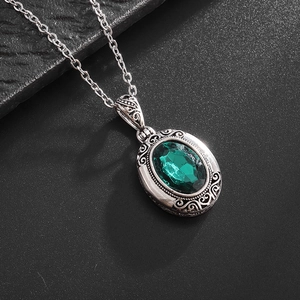 Vue détaillée du collier en filigrane argenté avec pierre ovale verte et gravure vintage
