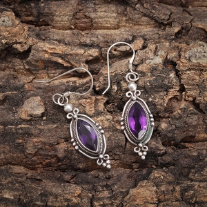 Detail of amethyst earrings with vintage silver frames on natural wood background