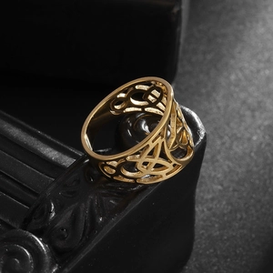 Macro shot of gold-plated hollow Celtic knot ring on a premium textured black base