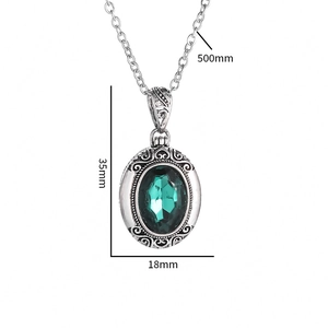 Vue détaillée du pendentif argenté avec zircon vert et motifs filigranes ciselés