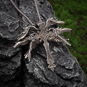 Macro detail of vintage gothic wing cross pendant on dark textured rock surface