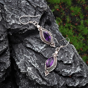 Vintage silver earrings with marquise-cut purple amethyst on dark stone and moss
