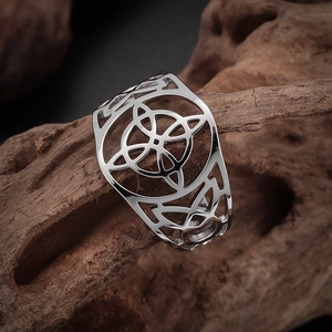 Detailed close-up of a silver Celtic knot cutout ring on a rustic wooden base