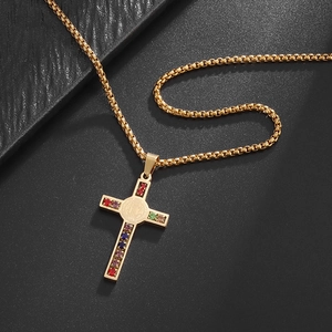Detail of gold cross pendant with colorful zircon stones on black leather background