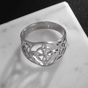 Macro top view of silver Celtic knot hollow carved stainless steel ring on marble